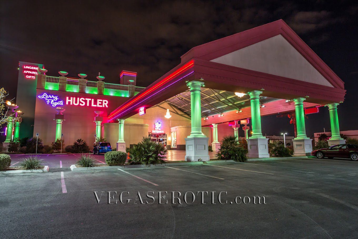 Hustler strip club lit up with neon pinks and greens accenting the building